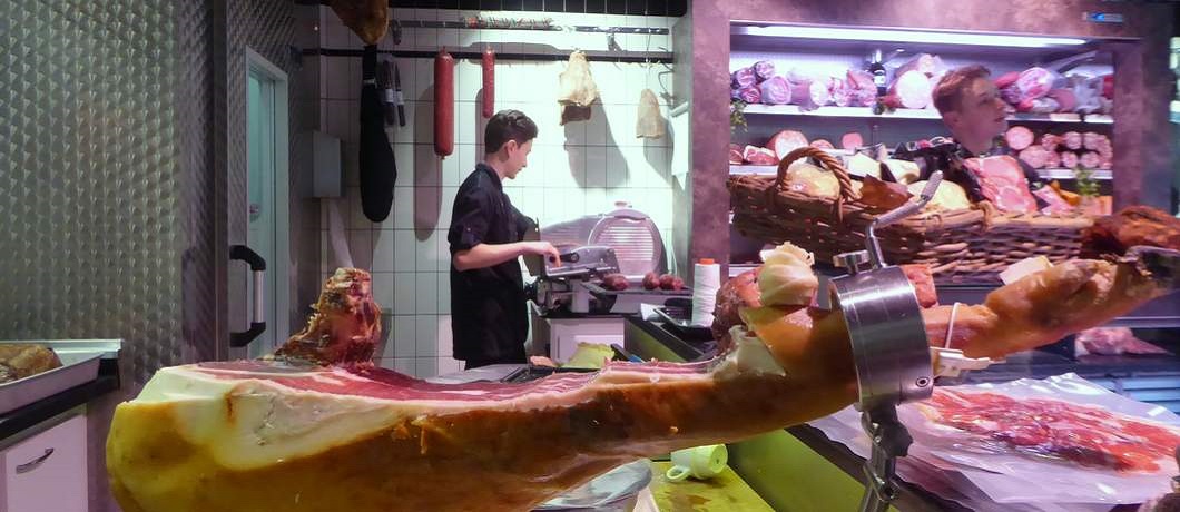 Een Belotta ham wordt in dunne plakjes gesneden bij slagerij de Wit