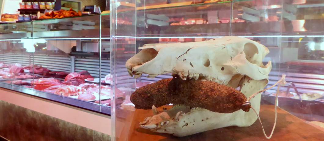 Mooie blikvanger in slagerij de Wit: een schedel met een worst tussen de kaken geklemd