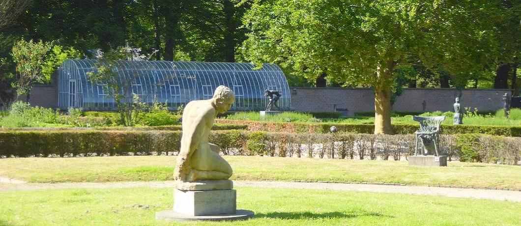 Een denker met op de achtergrond de orangerie in beeldenpark De Havixhorst