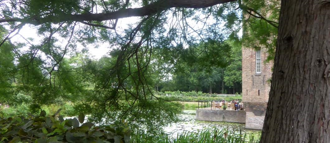 Het terras aan de slotvijver van Slot Zuylen waar tafels en stoelen staan en je heerlijk zit