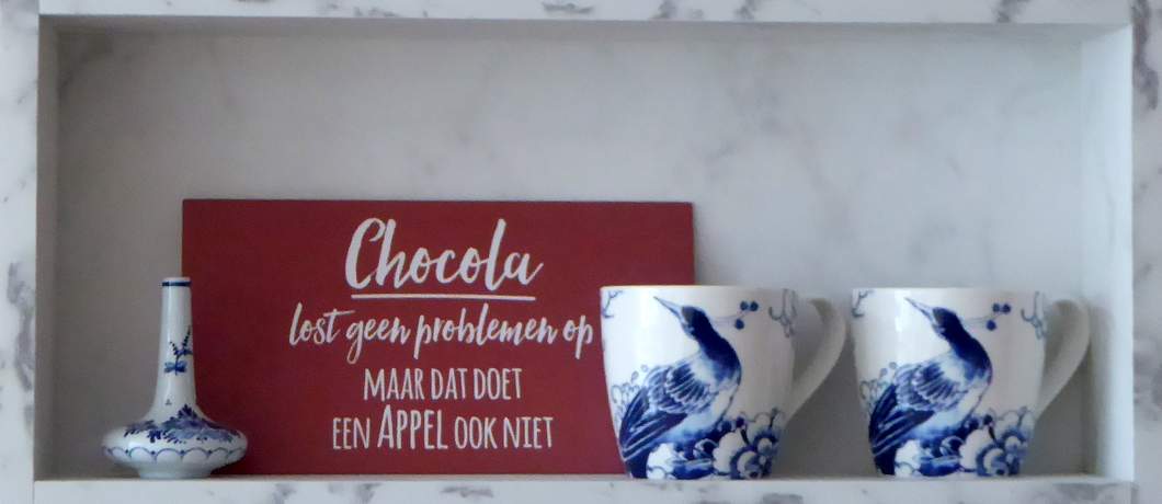 Geruststellende spreuk aan de muur bij Koek en Chocolade: Chocola lost geen problemen op, maar dat doet een appel ook niet