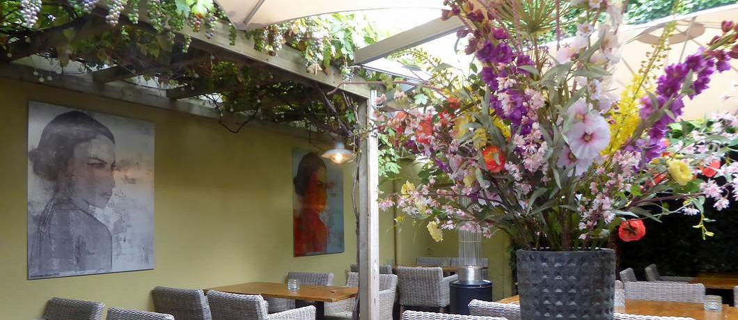 Binnenplaats met druivenranken en bloemen bij restaurant Verso in Enschede