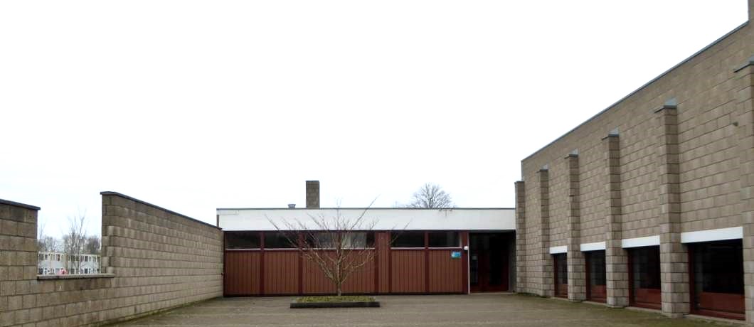 De muren rond de toegang van de hervormde kerk lopen op naar God.