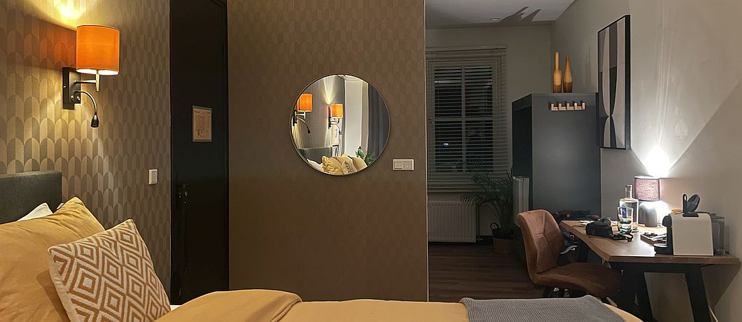 Kamer met open badkamer Oog voor detail zoals flessen en klerenhangers bij B&B Stadsslaperij Tilburg