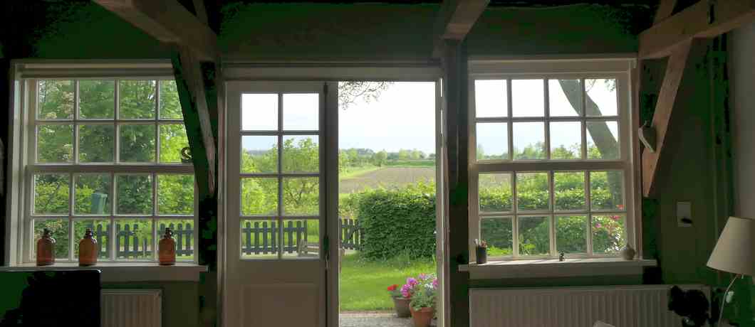 Uitzicht over de polder vanuit de zitkamer van het vakantiehuis in Terhofstede.