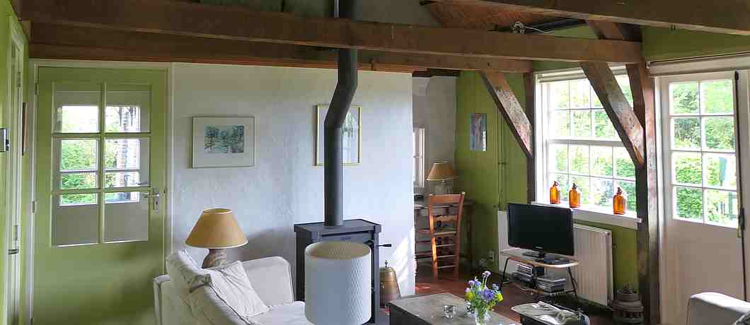 De zitkamer met lekkere banken en een houtkachel van het vakantiehuis in Terhofstede.