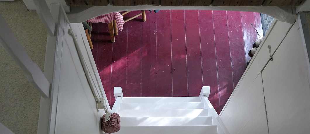 De steile trap vanuit de keuken naar de zolder De zitkamer met lekkere banken en een houtkachel van het vakantiehuis in Terhofstede.