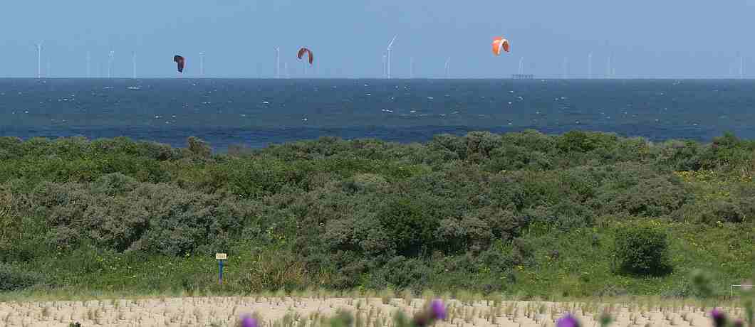 Uitzicht vanaf Kijkduin over de zee en kitesurfers tijdens de wandeling Kunst en Historie rond Ockenburgh.