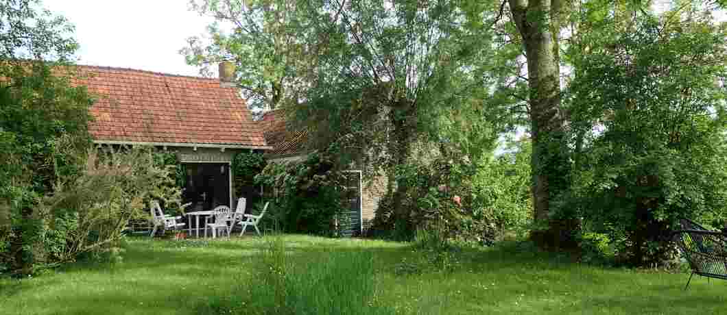Vanuit de tuin zicht op het woonhuis en de voormalige werkplaats van het vakantiehuis in Terhofstede.
